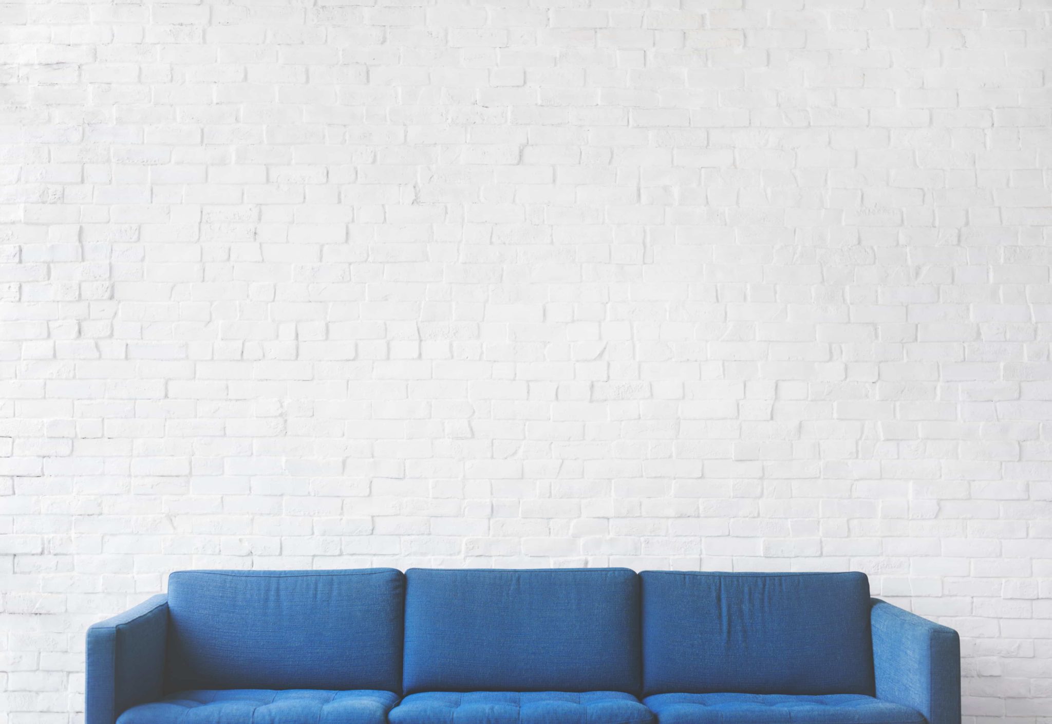 Image of blue sofa in front of white brick wall
